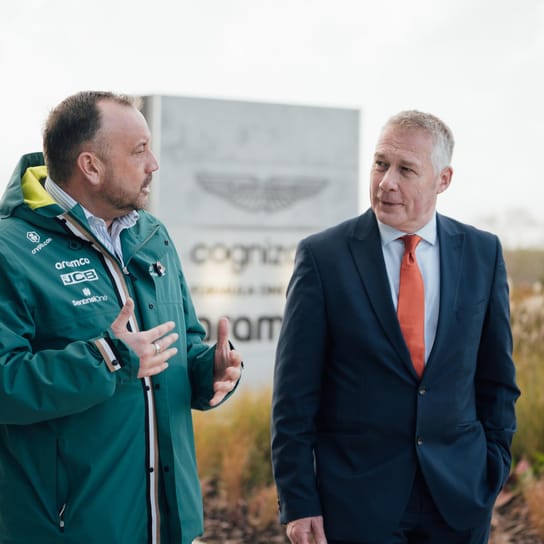 ชายสองคนกำลังพูดคุยหน้าตึกของ Aston Martin