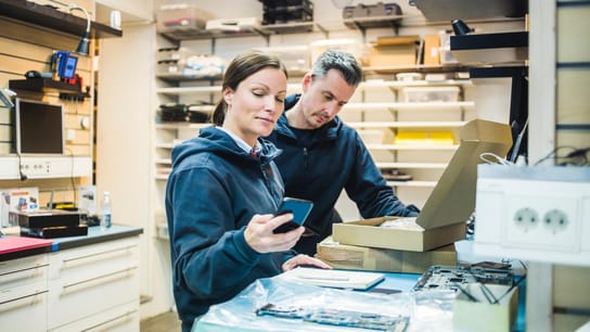 Engineer using mobile phone by colleague in workshop