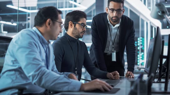 Drie mannen rond een computer
