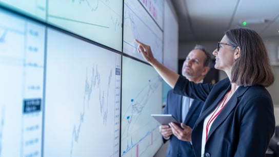 Two people discussing by wall screens.