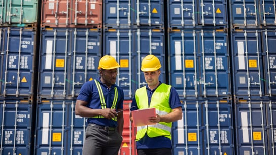 Two Commercial dock workers examining and confirm shipment at cargo container yard