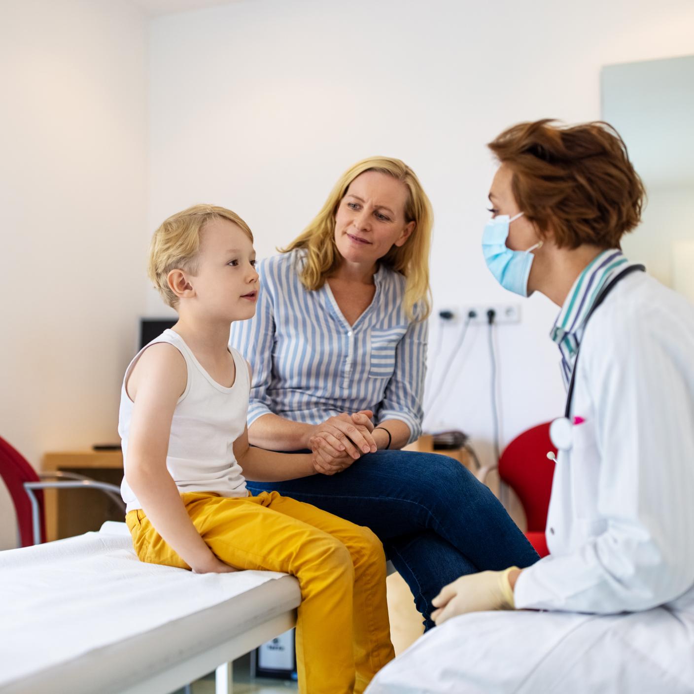 Pediatrician examining a boy patient in clinic.