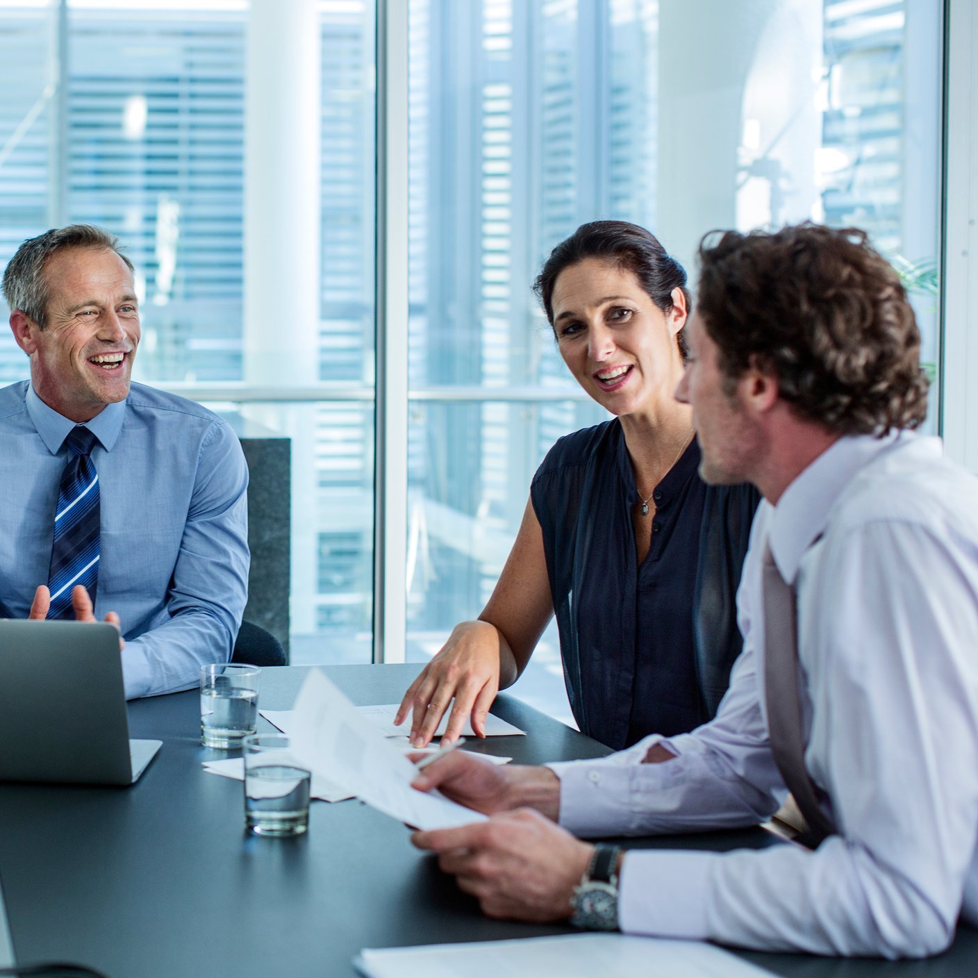 Happy business professionals discussing at conference table in office