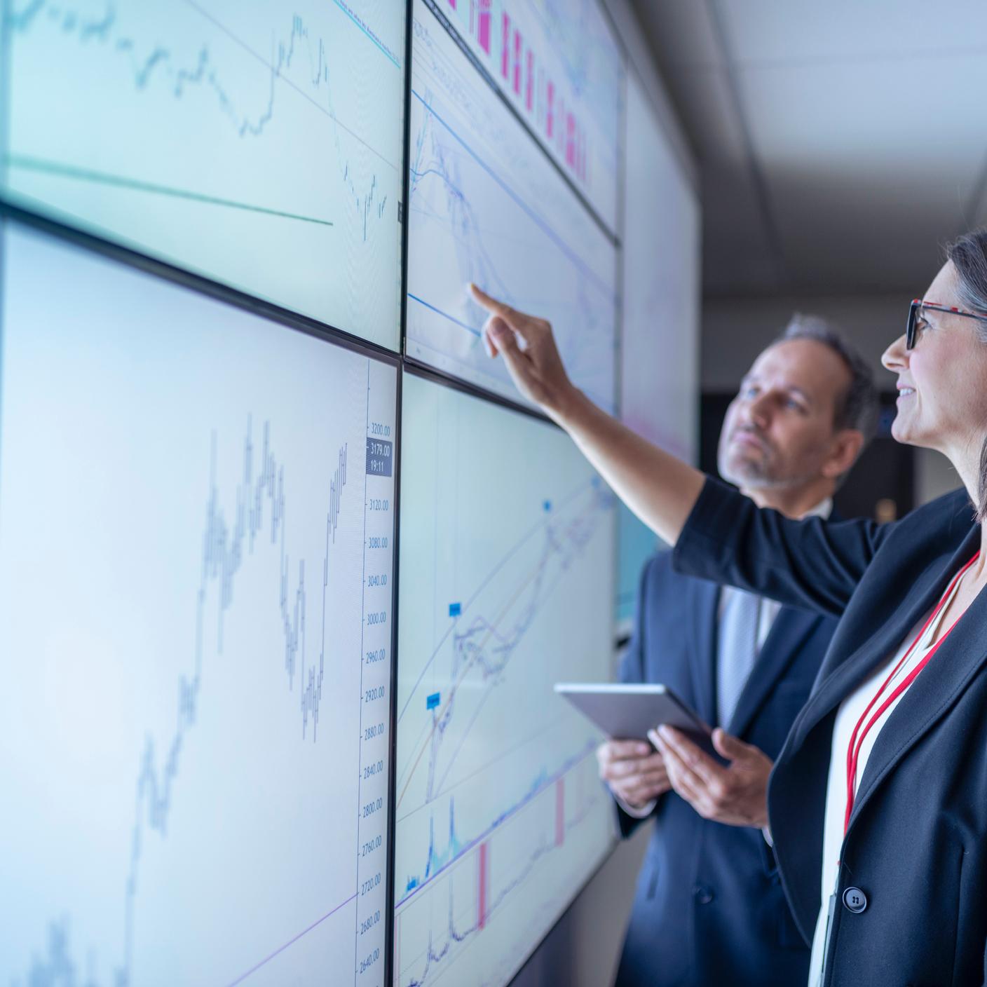 Uomini d'affari lavorano ai grafici su schermi interattivi