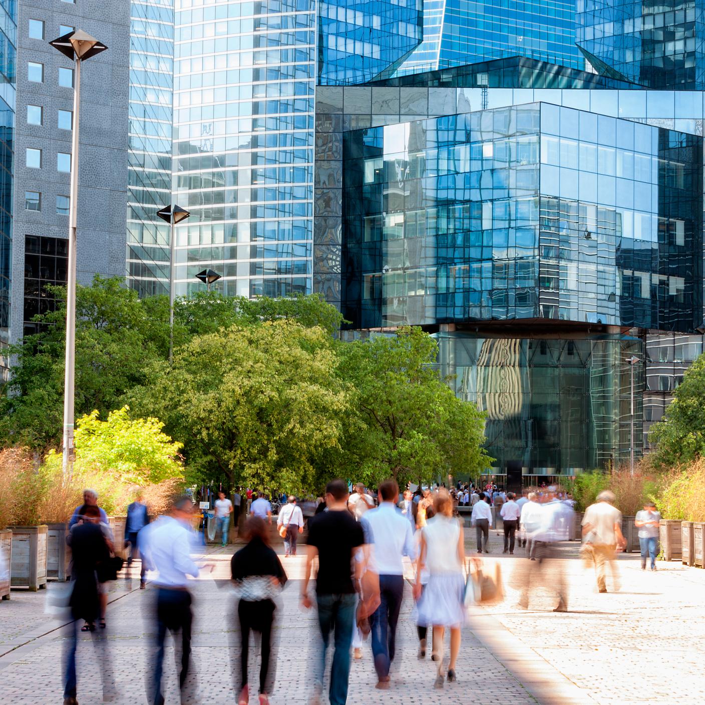 crowd of business people walking through financial district towards modern office building, La Defense, Paris, France