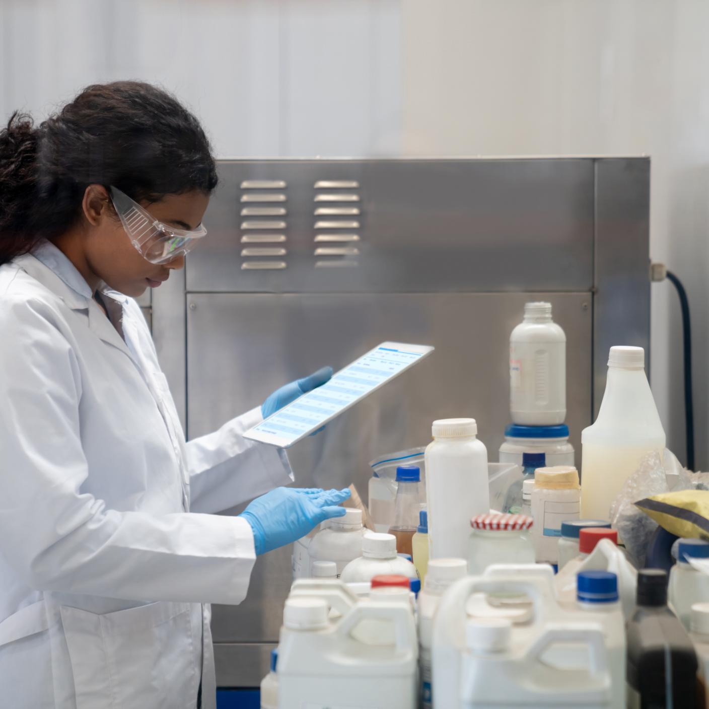 Latin American female chemist doing research while working at an industrial lab using a digital tablet.