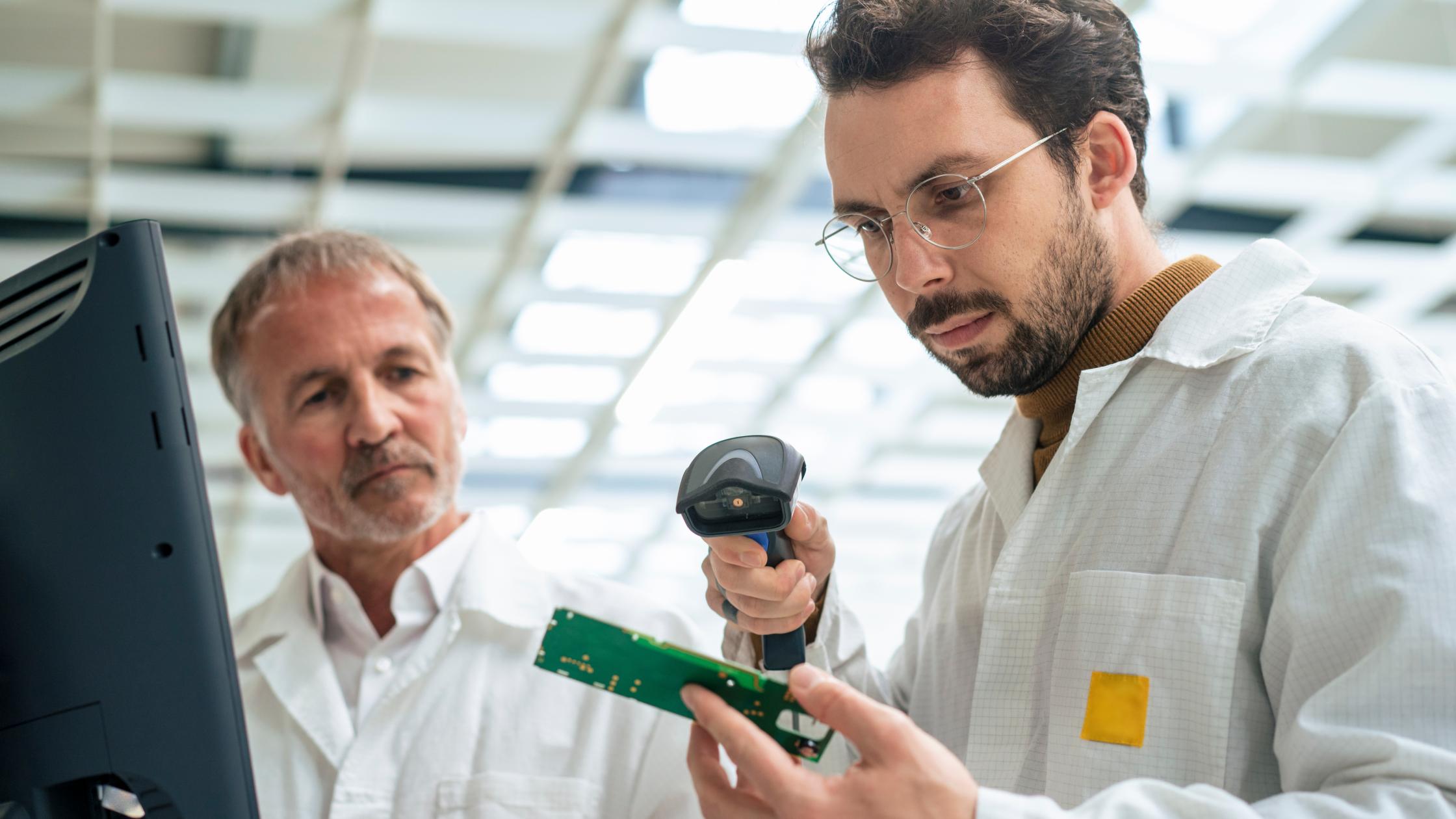Engineer scanning circuit board with bar code scanner at industry.