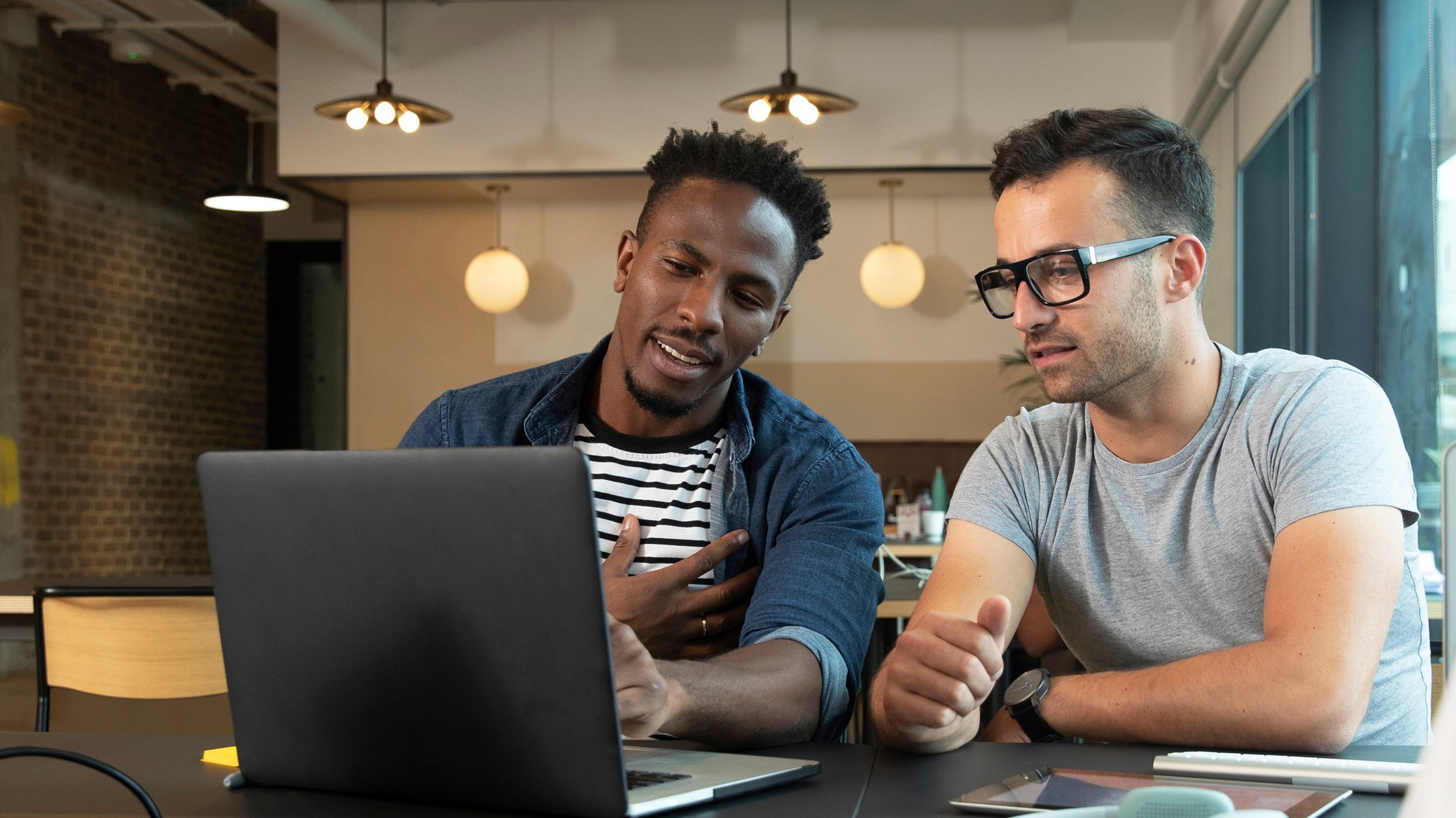 Creative, casual businessmen meeting, planning at laptop in office